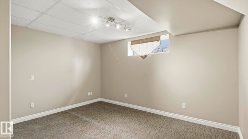 Room featuring neutral-toned walls, textured carpet flooring, and white baseboards - 6116 53 Avenue, Beaumont, AB - Indoor Photo Showing Other Room