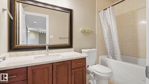 Bathroom featuring a wood-finish vanity with an integrated rectangular sink and a light-toned countertop - 6116 53 Avenue, Beaumont, AB - Indoor Photo Showing Bathroom