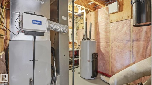 Utility room featuring a central humidifier, furnace, hot water heater, and exposed insulation - 6116 53 Avenue, Beaumont, AB - Indoor Photo Showing Basement