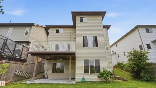 Three-story home featuring light-colored horizontal siding, a second-story balcony with white railings, and a ground-level concrete patio - 6116 53 Avenue, Beaumont, AB - Outdoor With Exterior
