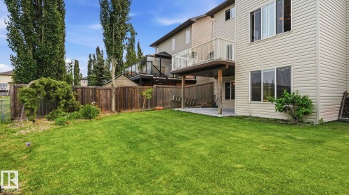 Expansive fenced backyard featuring a manicured lawn, established landscaping, and mature trees - 6116 53 Avenue, Beaumont, AB - Outdoor