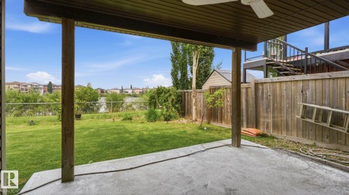 Covered concrete patio opening to a fenced backyard featuring a storage shed and a distant body of water - 6116 53 Avenue, Beaumont, AB - Outdoor With Exterior