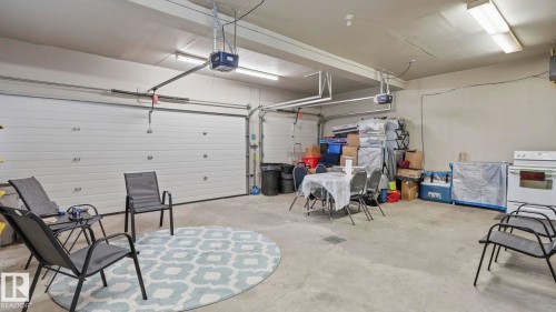 Spacious garage featuring two overhead doors with automatic openers, fluorescent lighting, and concrete flooring - 6116 53 Avenue, Beaumont, AB - Indoor Photo Showing Garage