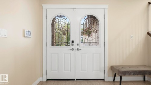Double entry doors featuring arched leaded glass panels and matte chrome hardware - 6116 53 Avenue, Beaumont, AB - Indoor Photo Showing Other Room