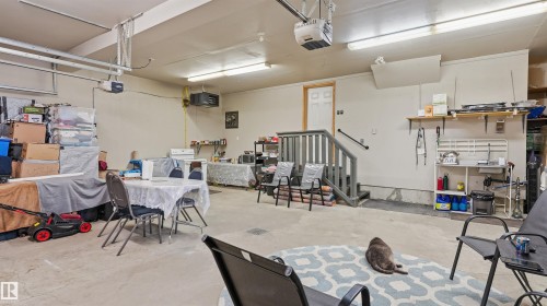 Spacious garage interior featuring a concrete floor, overhead fluorescent lighting, and two garage door openers - 6116 53 Avenue, Beaumont, AB - Indoor Photo Showing Garage