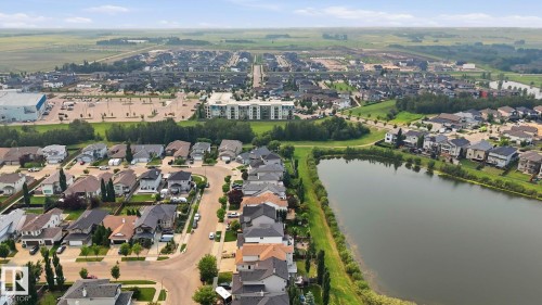 Aerial overview showcasing a residential community with varied rooflines and a prominent central water feature - 6116 53 Avenue, Beaumont, AB - Outdoor With Body Of Water With View