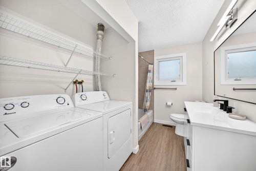 Bathroom featuring a white vanity with a rectangular sink, matte black faucet, and a wall-mounted mirror - 12721 117 Street Nw, Edmonton, AB 
