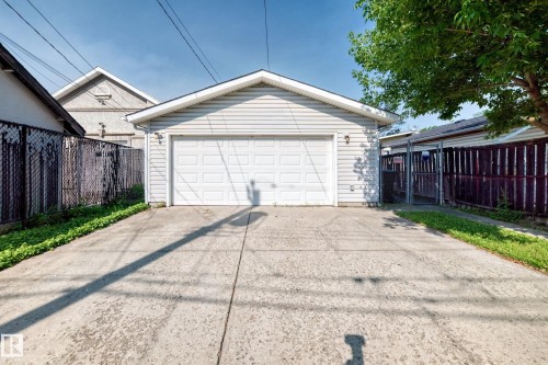 Two-car garage with a paneled door, exterior wall lighting, and concrete driveway - 12721 117 Street Nw, Edmonton, AB 