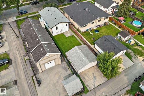 Expansive property with multiple structures, including a long building featuring a large garage door, an additional detached garage, and a spacious green lawn - 12721 117 Street Nw, Edmonton, AB 