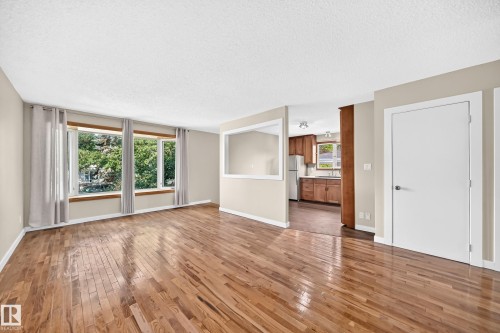 Hardwood flooring, painted walls, multiple windows, built-in wall niche, and a solid core door - 12721 117 Street Nw, Edmonton, AB 