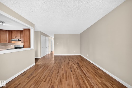 Hardwood flooring throughout, kitchen with wood cabinetry, stainless steel range, and track lighting, and a neutral wall palette - 12721 117 Street Nw, Edmonton, AB 