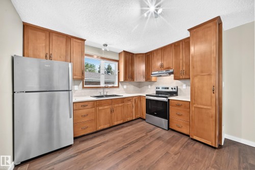 Wood-finish flooring, stainless steel appliances, light-toned cabinetry, light-toned countertops, and a subway tile backsplash - 12721 117 Street Nw, Edmonton, AB 