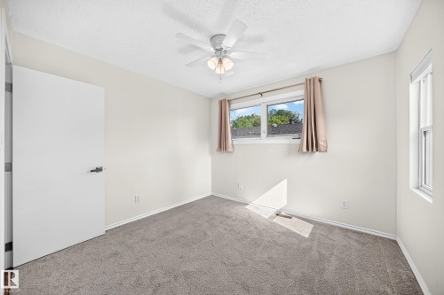 Wall-to-wall carpeting, ceiling fan with integrated lighting, multiple windows providing natural light, and a flat-panel interior door with dark hardware - 12721 117 Street Nw, Edmonton, AB 