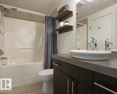 Bathroom featuring a combined shower and tub, tile flooring, a vessel sink, a dark wood-finish vanity, and wall-mounted shelving - 