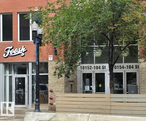Brick exterior with large storefront windows and prominent street numbers - #605 10152 104 St Nw, Edmonton, AB 