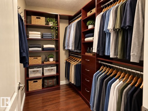 Custom closet system featuring rich wood-finish cabinetry, extensive shelving, multiple hanging rods, and integrated drawers - 16893 58A Street Nw, Edmonton, AB 