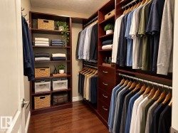 Custom closet system featuring rich wood-finish cabinetry, extensive shelving, multiple hanging rods, and integrated drawers - 