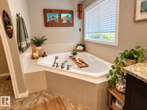 Corner soaking tub featuring deck-mounted fixtures, tiled surround, and a window with blinds - 16893 58A Street Nw, Edmonton, AB 