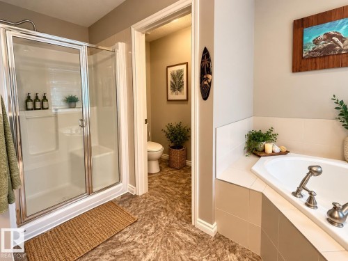 Walk-in shower with clear glass enclosure and chrome hardware, corner soaking tub with deck-mounted fixtures, and textured flooring - 16893 58A Street Nw, Edmonton, AB 