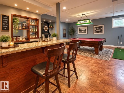 Built-in bar with a granite countertop and wood-finish cabinetry - 16893 58A Street Nw, Edmonton, AB 
