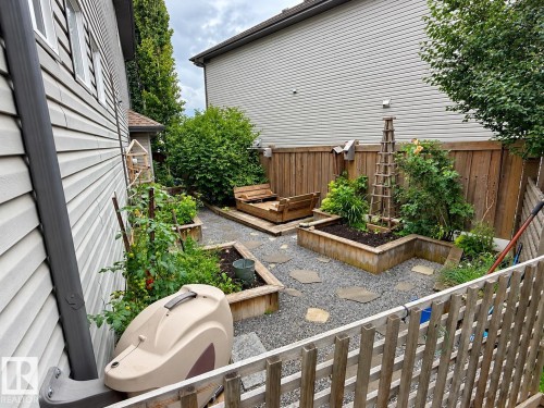 Private backyard featuring raised garden beds, gravel ground cover, stepping stones, and wood fencing - 16893 58A Street Nw, Edmonton, AB 