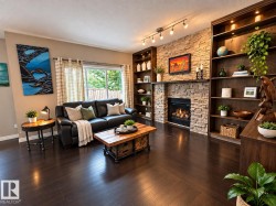 Gas fireplace with a stone surround, built-in shelving with integrated lighting, dark wood-finish flooring, and sliding glass doors - 