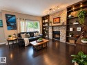 Gas fireplace with a stone surround, built-in shelving with integrated lighting, dark wood-finish flooring, and sliding glass doors - 16893 58A Street Nw, Edmonton, AB 