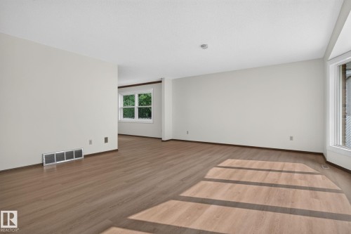Spacious room featuring wood-finish flooring, white walls, and white trim - 12121 42 Street Nw, Edmonton, AB - Indoor Photo Showing Other Room