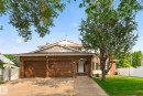 Brick exterior featuring a two-car garage with wood-finish doors - 12121 42 Street Nw, Edmonton, AB  - Outdoor 