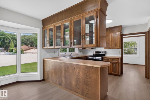 Kitchen featuring wood-finish cabinetry, a breakfast bar, and wood-finish flooring - 12121 42 Street Nw, Edmonton, AB - 