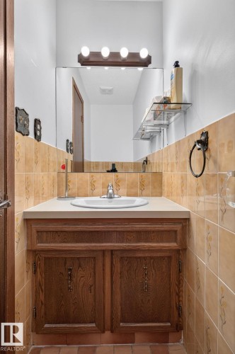 Bathroom vanity with wood-finish cabinetry, a drop-in sink, and a light-colored countertop - 12121 42 Street Nw, Edmonton, AB - Indoor Photo Showing Bathroom