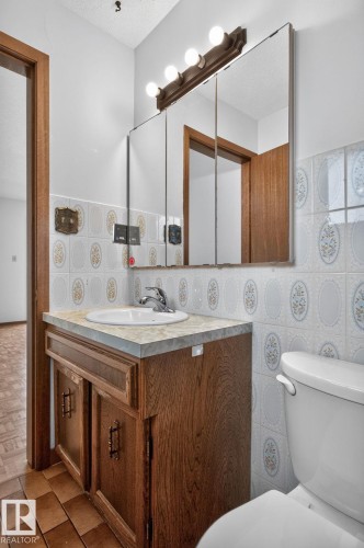 Bathroom vanity with wood-finish cabinetry, a drop-in sink, and a light-colored countertop - 12121 42 Street Nw, Edmonton, AB - Indoor Photo Showing Laundry Room