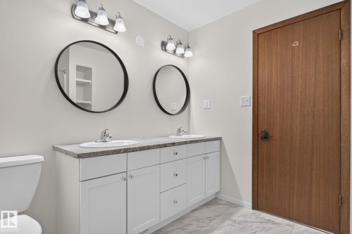 Dual vanity featuring white shaker cabinetry, undermount sinks, and stone-finish countertops - 12121 42 Street Nw, Edmonton, AB - Indoor Photo Showing Bathroom