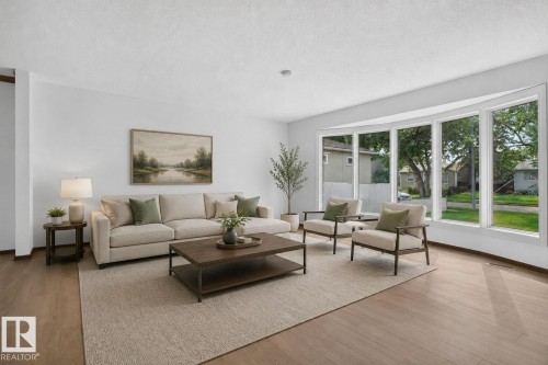 Bright living area featuring wood-finish flooring and a large bay window - 12121 42 Street Nw, Edmonton, AB - Indoor Photo Showing Living Room