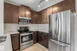 Modern kitchen featuring stainless steel appliances, dark wood-finish cabinetry, light countertops, a white subway tile backsplash, and tile flooring - 