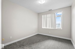Carpeted room with light neutral wall paint, white trim, and a window featuring vertical blinds - 