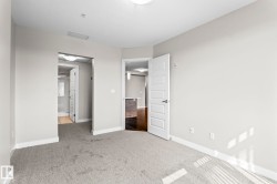 Carpeted room with light neutral walls, featuring a five-panel interior door with brushed nickel hardware - 