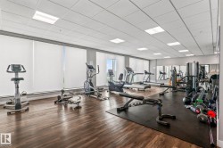 Fitness center featuring cardio and strength equipment, wood-finish flooring, recessed lighting, and wall-mounted mirrors - 