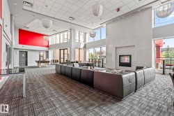Spacious common area featuring an integrated fireplace, expansive window walls, and textured carpeting - 