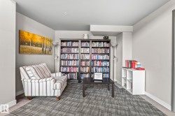 Dedicated library space featuring wall-to-wall shelving, patterned carpeting, a large wall art piece, and neutral wall tones - 
