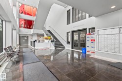 Bright, expansive lobby featuring polished stone-finish flooring, a contemporary reception desk, and a multi-story atrium with large windows - 
