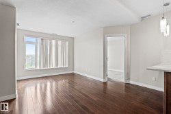 Spacious room featuring wide plank wood-finish flooring, a large window, light-toned walls, and white trim - 