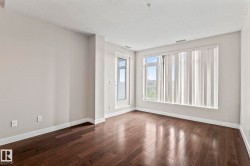 Spacious interior featuring dark wood-finish flooring, light neutral walls, and extensive window light with vertical blinds - 