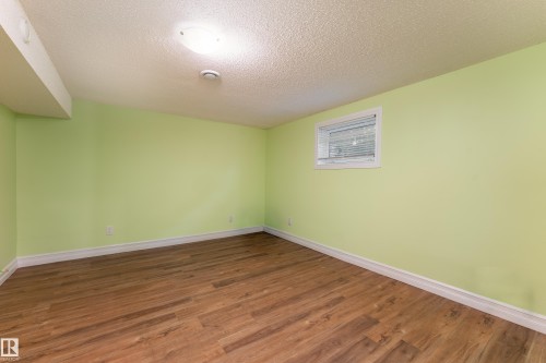 Wood-finish flooring with light green walls, white trim, and a window with blinds - 17928 93 Ave Nw, Edmonton, AB 