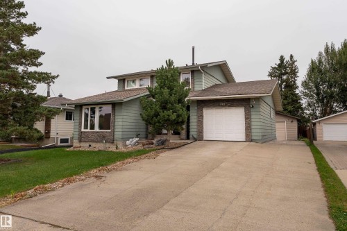Split-level residence featuring a light green siding exterior, an attached single-car garage with a white door, and an additional detached single-car garage - 17928 93 Ave Nw, Edmonton, AB 