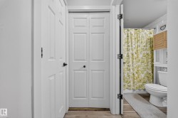 White panel doors, wood-finish flooring, white toilet, and built-in white shelving - 