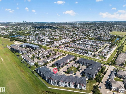 Aerial perspective showcasing a multi-building complex with ample surface parking, surrounded by green spaces and a residential community - #419 920 156 St Nw, Edmonton, AB 