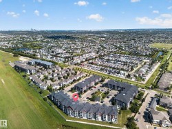 Aerial perspective showcasing a multi-building complex with ample surface parking, surrounded by green spaces and a residential community - 