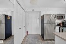 Modern kitchen featuring stainless steel appliances including refrigerator, microwave, and range; light wood-finish countertops; white cabinetry with brushed nickel hardware; and wood-finish flooring throughout - #419 920 156 St Nw, Edmonton, AB 