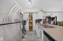 Galley kitchen featuring stainless steel appliances, including a French-door refrigerator and gas cooktop, paired with light-finish countertops and white cabinetry - #419 920 156 St Nw, Edmonton, AB 